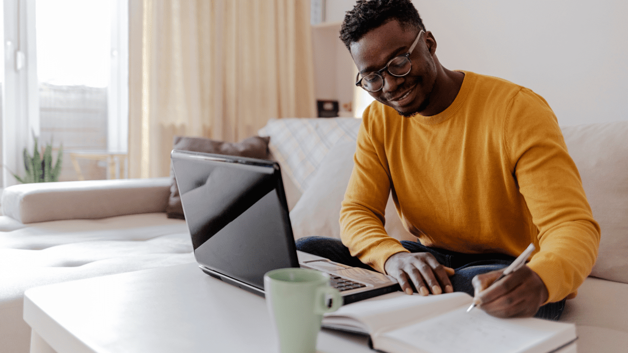 A self-employed individual working at a desk, managing finances with documents and a laptop.